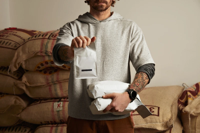 Tattooed Barista Holds Black Package Bags with Freshly Baked Coffee Beans Ready Sale Delivery Brewing